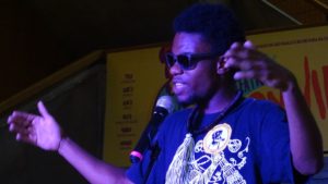Seorang performer sedang membaca puisi dengan kemasan hip hop yang memikat masyarakat setempat