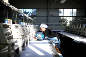 Perempuan hui bekerja di mesin bordir di pabrik pakaian jadi Wan Ti Ni, yang mengkhususkan diri memproduksi pakaian Hui dan Islam tradisional, di Wuzhong, Cina. (foto: Adam Dean/The New York Times)